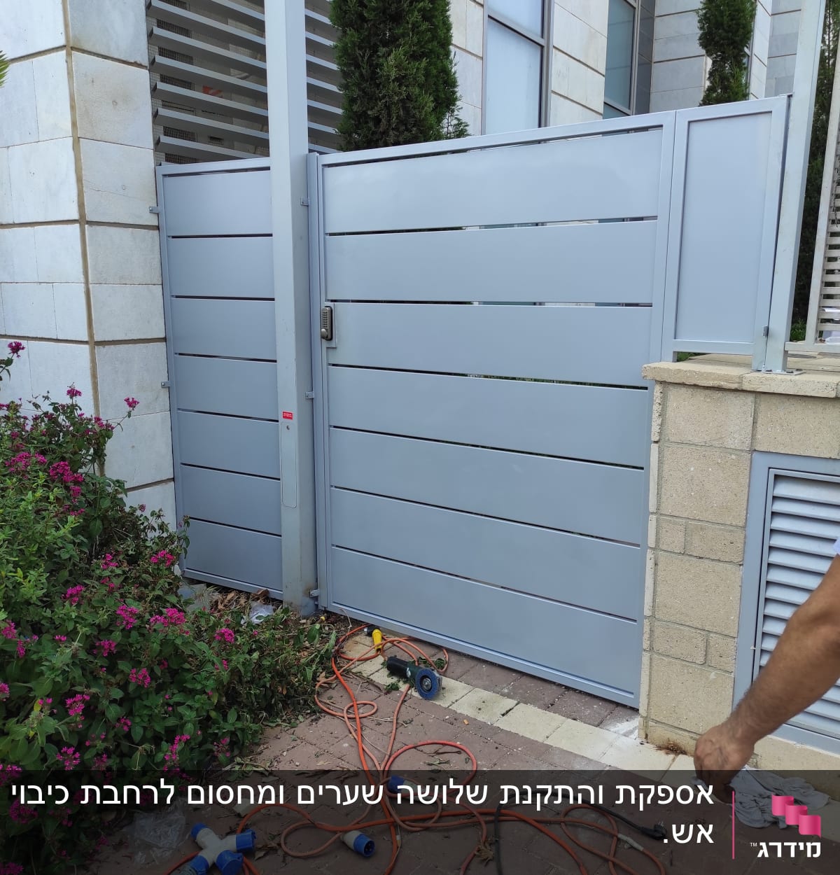 שער מתכת אפור עם מסגרת, כבלים וכלים על הקרקע